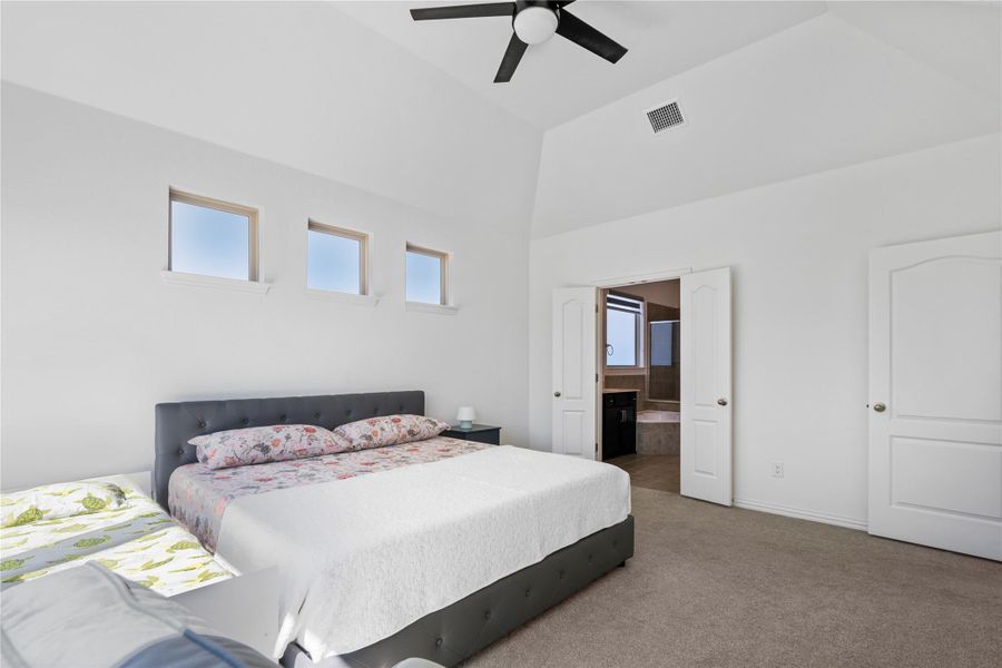 A well-lit bedroom with soaring vaulted ceilings and plush carpeting offers an inviting and comfortable retreat. A well-lit bedroom with soaring vaulted ceilings and plush carpeting offers an inviting and comfortable retreat.