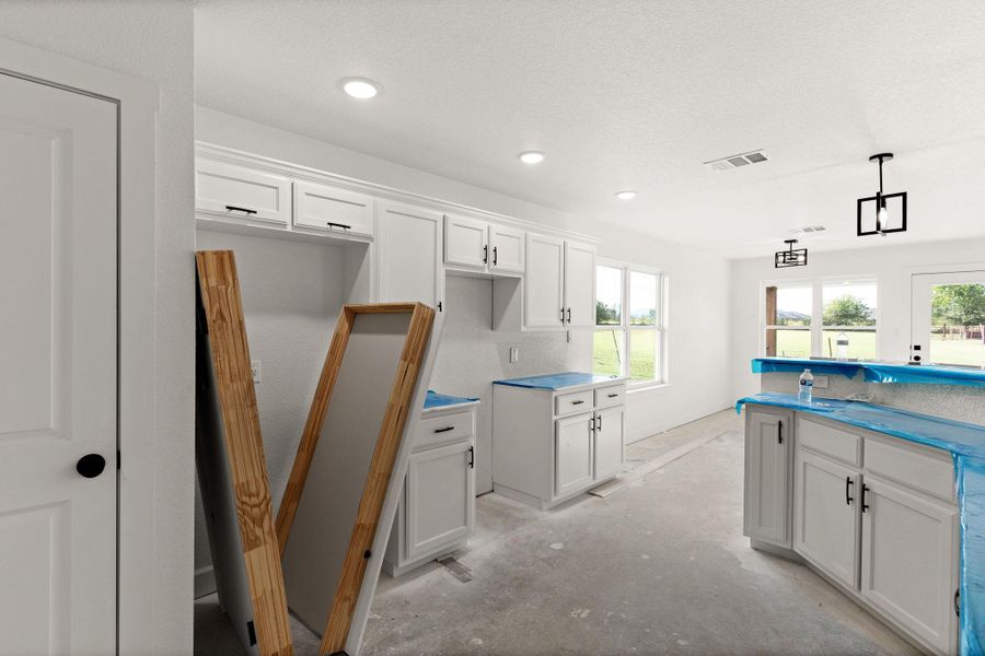 Kitchen with white cabinetry, recessed lighting, concrete floors, and hanging light fixtures Kitchen with white cabinetry, recessed lighting, concrete floors, and hanging light fixtures