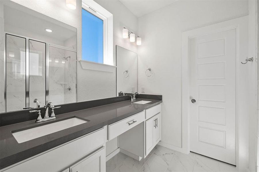 Bathroom with a marble finish shower, light marble finish flooring, and double vanity Bathroom with a marble finish shower, light marble finish flooring, and double vanity