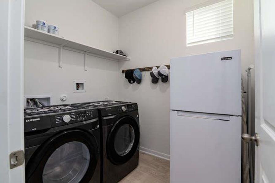 Laundry room with independent washer and dryer and light wood-style flooring