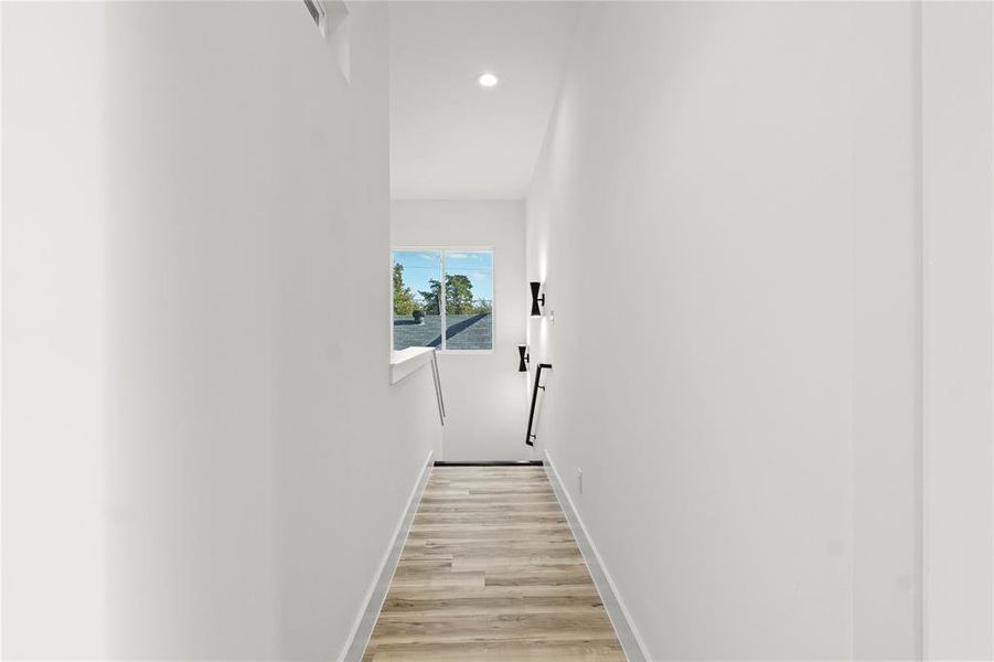 Corridor with light wood finished floors and recessed lighting
