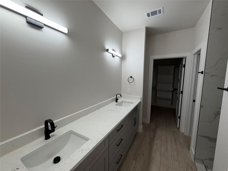 Dual vanities with sleek black fixtures enhance this well-appointed bath with walk-in closet access.