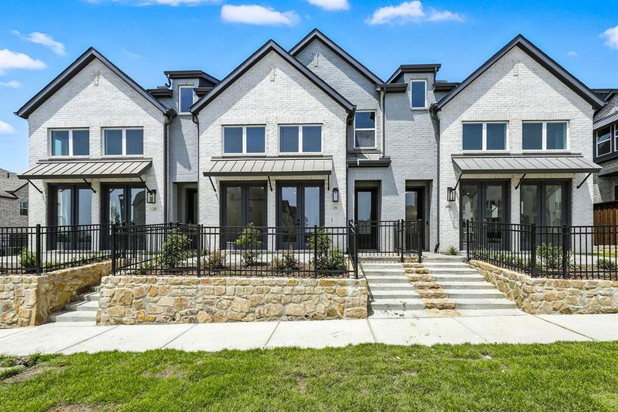 View of front of property featuring a fenced front yard, brick siding, a standing seam roof, and a metal roof View of front of property featuring a fenced front yard, brick siding, a standing seam roof, and a metal roof