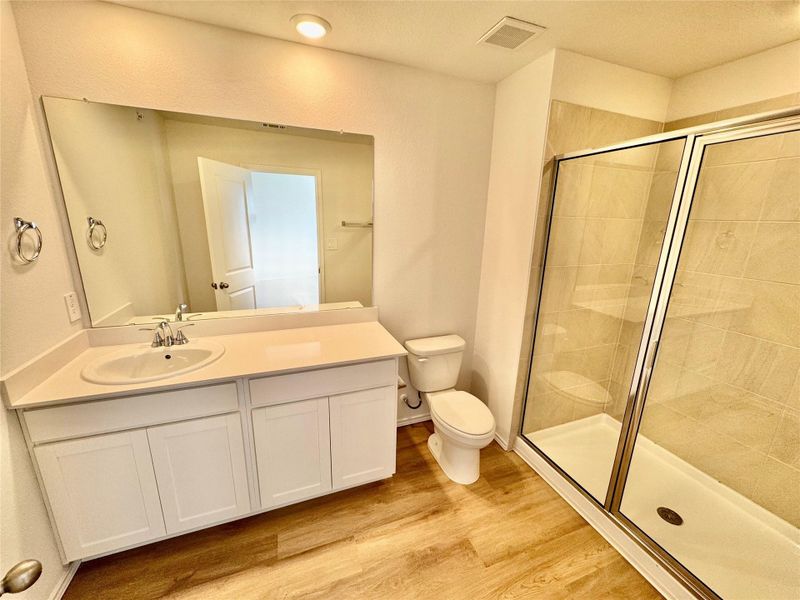 Bathroom with vanity, a shower stall, and light wood-style flooring