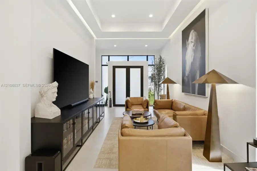 Tray ceiling featuring integrated recessed lighting, smooth finish walls, and glass-paneled double entry doors with dark metal framing