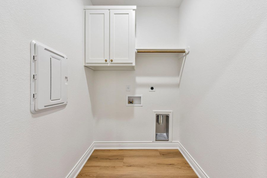 Functional laundry space featuring durable wood flooring and convenient cabinetry for organized utility. Functional laundry space featuring durable wood flooring and convenient cabinetry for organized utility.