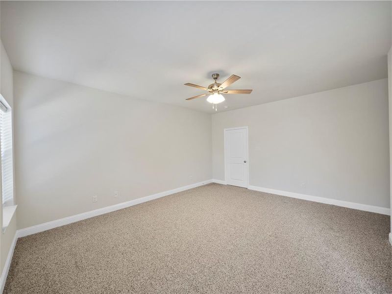 Unfurnished room featuring light carpet, ceiling fan, and baseboards