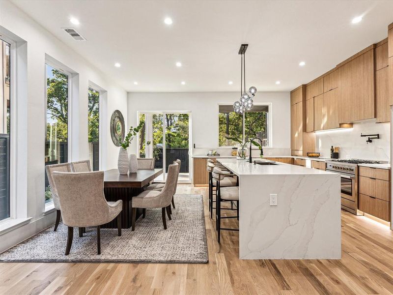 Kitchen with stainless steel range, sink, pendant lighting, and light hardwood / wood-style floors