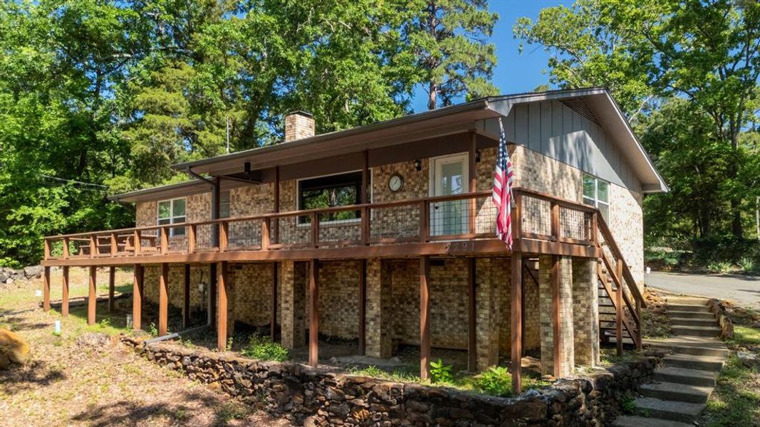 Brick home featuring an elevated wood deck