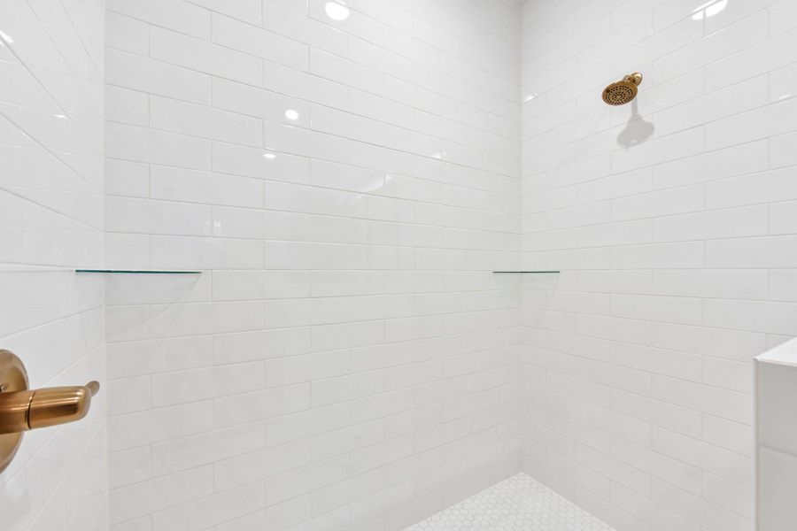 A well-appointed shower features sleek white subway tile and a practical glass shelf. A well-appointed shower features sleek white subway tile and a practical glass shelf.