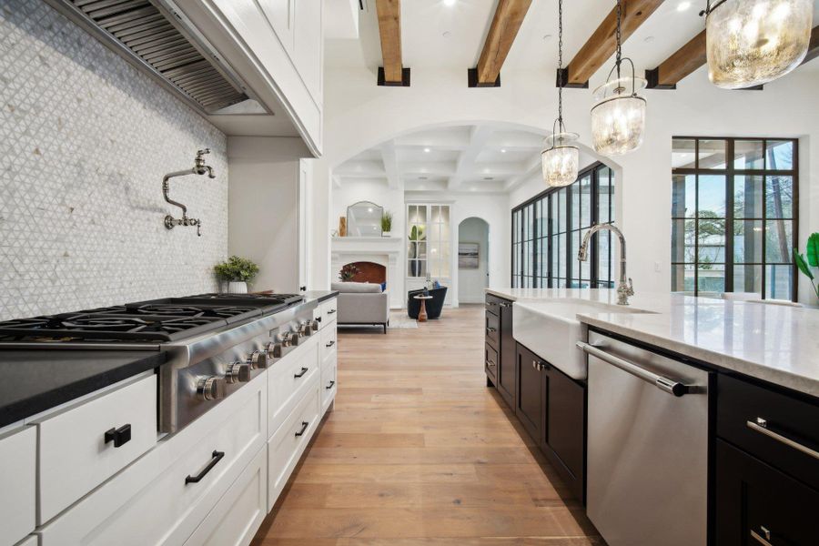 Kitchen with tasteful backsplash, light wood-type flooring, range hood, stainless steel appliances, and a sink