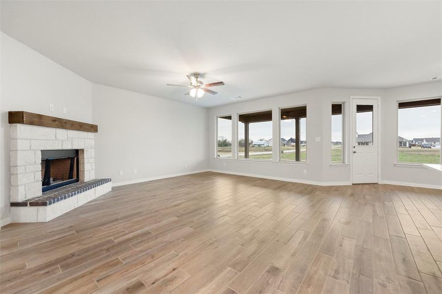 Unfurnished living room with wood finish floors, a fireplace, and ceiling fan Unfurnished living room with wood finish floors, a fireplace, and ceiling fan