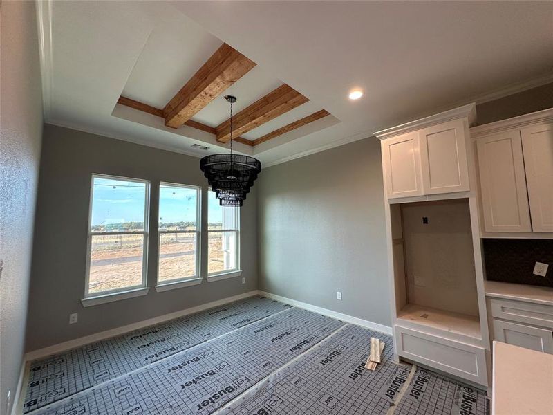 Unfurnished dining area featuring tile patterned flooring, ornamental molding, beamed ceiling, and an inviting chandelier