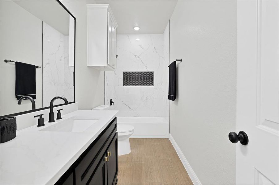 Full bathroom with tiled shower / bath, vanity, wood-type flooring, and toilet