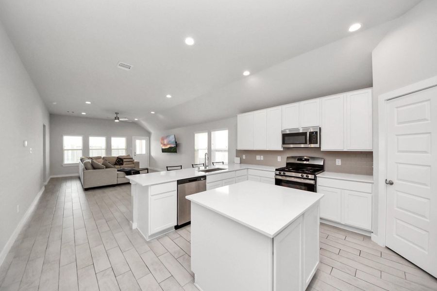 Spacious open-concept kitchen with quartz countertops, ample cabinetry, and a large island, seamlessly flowing into the dining and living areas. High ceilings and large windows throughout fill the space with natural light.