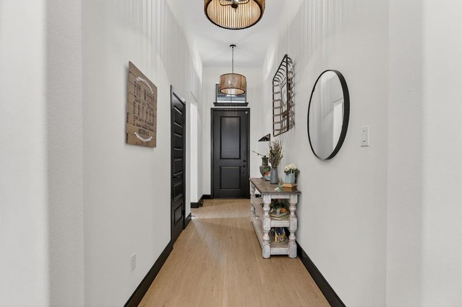 Hallway featuring wood-finish flooring, dark trim, and paneled doors
