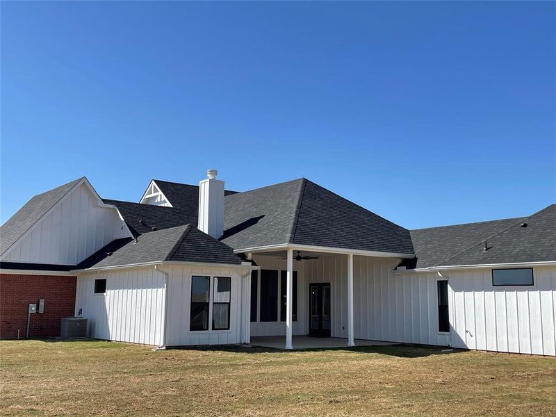 Back of property featuring a patio area, roof with shingles, ceiling fan, a yard, and a chimney