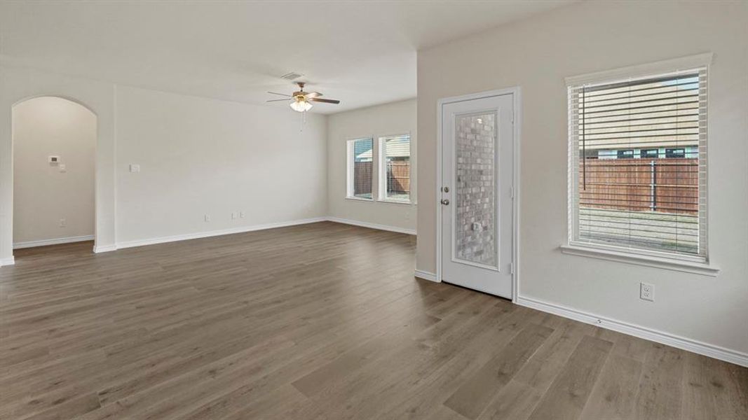 Empty room featuring arched walkways, light wood-style floors, and ceiling fan Empty room featuring arched walkways, light wood-style floors, and ceiling fan