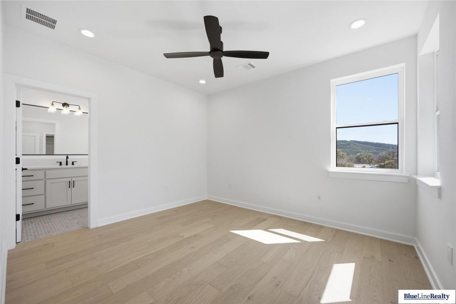 Unfurnished bedroom featuring light wood finished floors, ceiling fan, recessed lighting, and ensuite bathroom
