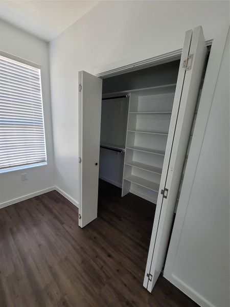 Ample storage solutions feature within this well-designed bedroom, complete with rich hardwood flooring.