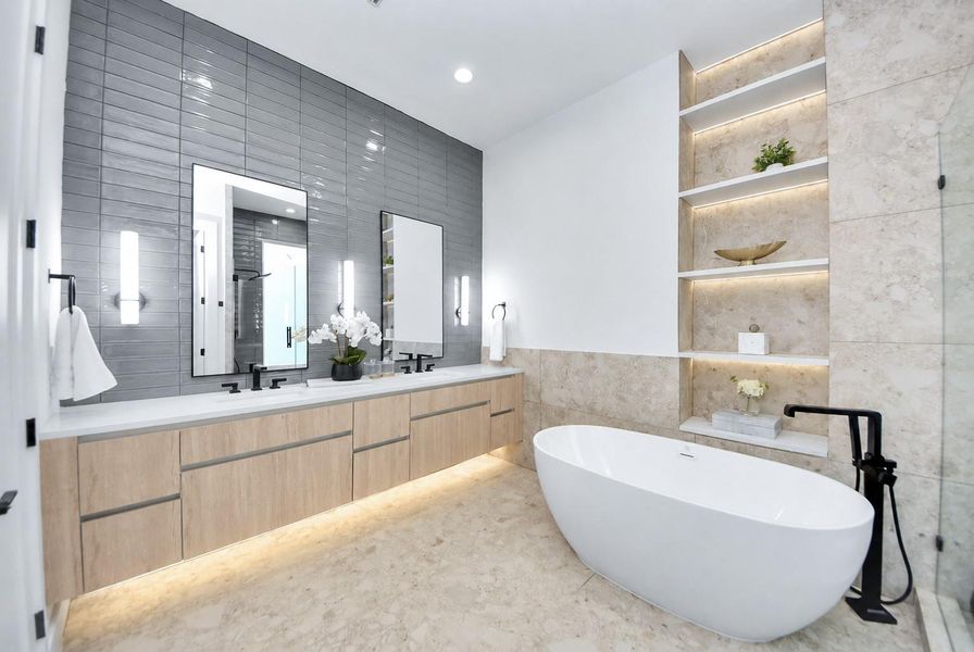 Primary bathroom featuring a double vanity, freestanding tub, and contemporary tilework.
