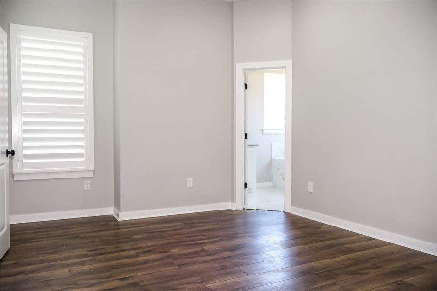 Unfurnished bedroom with dark wood finished floors and ensuite bath
