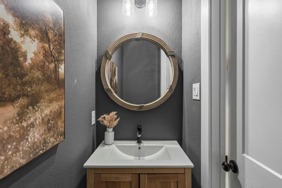 Conveniently located just off the Kitchen and Mud Room, the Powder Room is perfectly situated for guests and everyday use. This thoughtfully designed space features an undermount sink, a framed mirror, and enclosed storage, while a striking pop of color adds personality and visual interest.