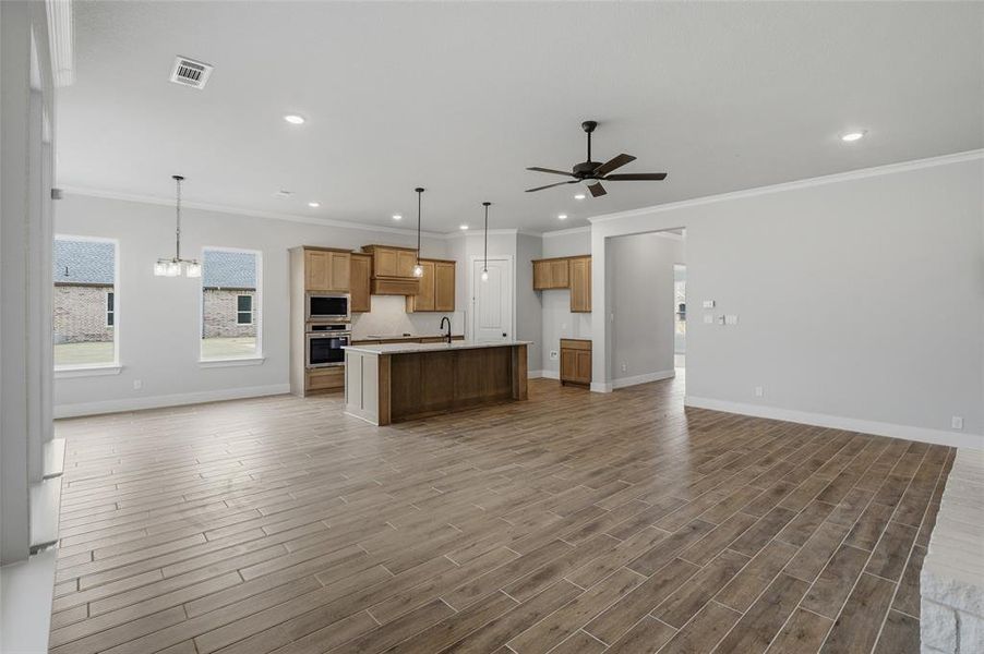 Kitchen with open floor plan, wood finish cabinetry, wood finish floors, an island with sink, and ceiling fan