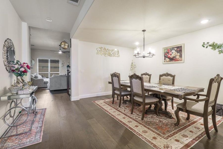 Dining area with dark wood-style flooring, hanging lights, and a ceiling fan