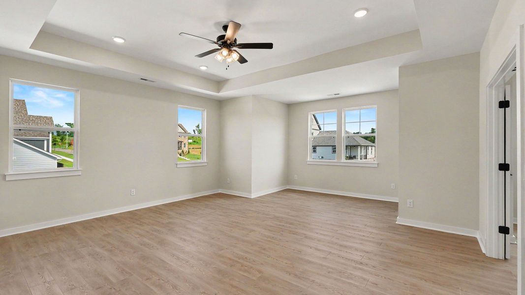 Second Floor primary bedroom with hardwood flooring, tray ceiling, and view of connected private study