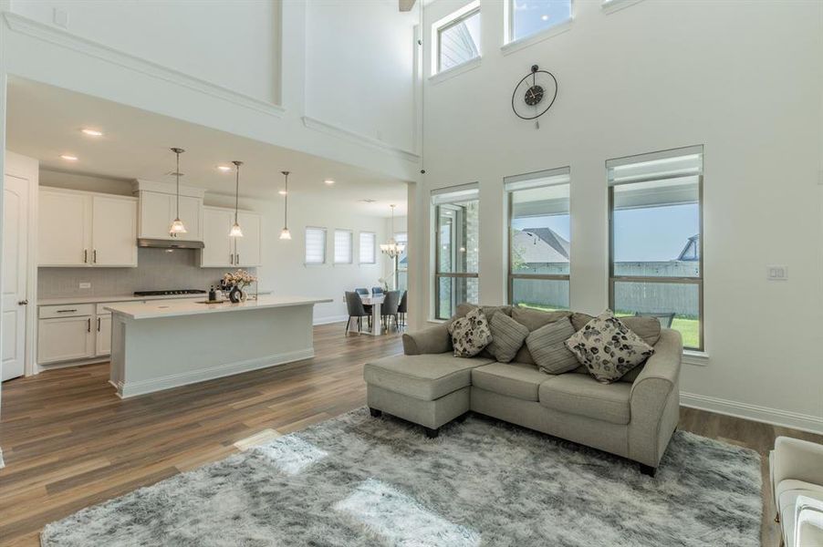 Open-concept living area featuring high ceilings, wood-finish flooring, and multiple windows
