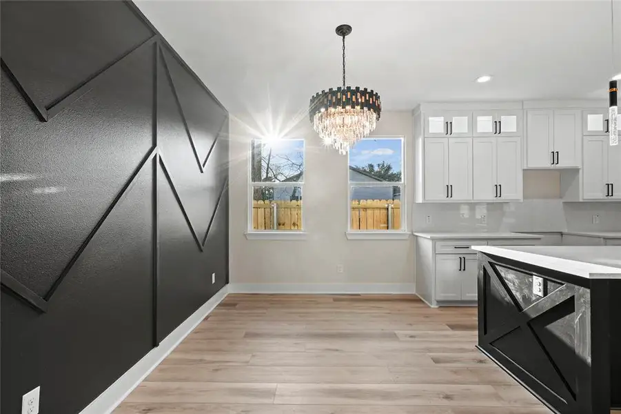 Kitchen with white cabinets, a chandelier, hanging light fixtures, and tasteful backsplash