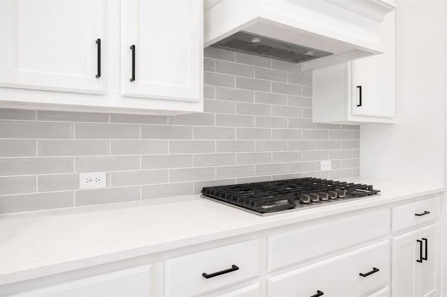 Kitchen featuring a gas cooktop, light grey subway tile backsplash, white shaker-style cabinetry, white countertops, and matte black hardware