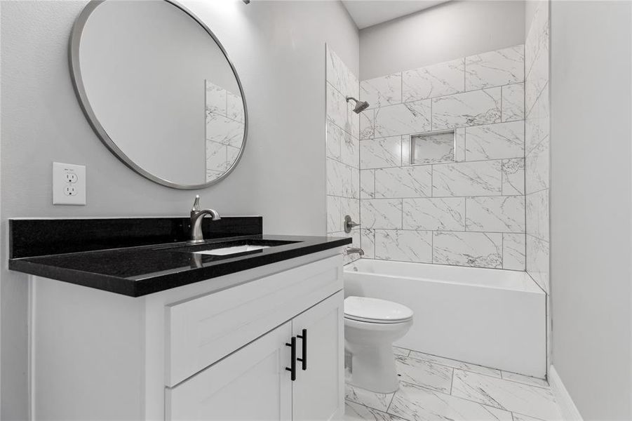 Bathroom with marble finish floor, washtub / shower combination, toilet, and vanity
