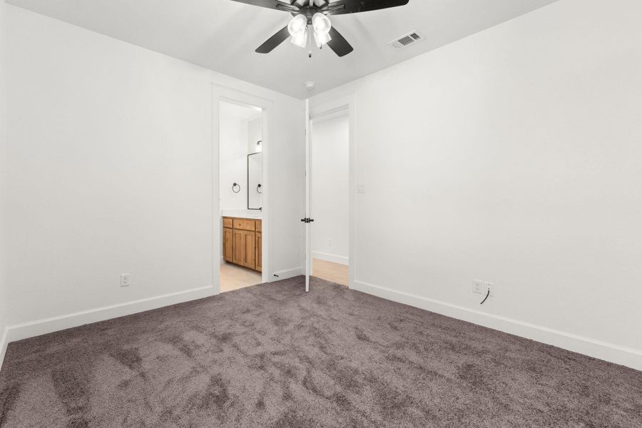 Unfurnished bedroom with light carpet, ensuite bath, and ceiling fan