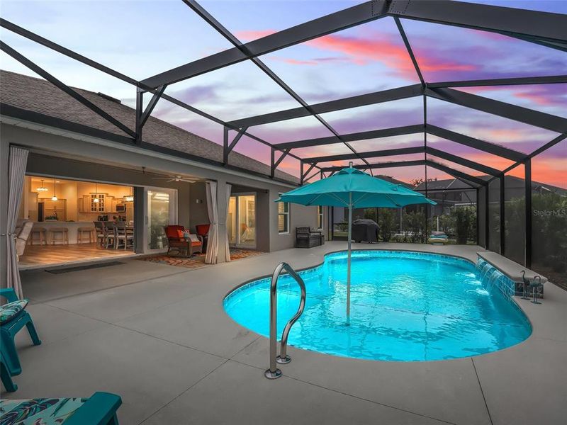 Pool area with expanded patio space, shallow shelf with umbrella, and three waterfalls