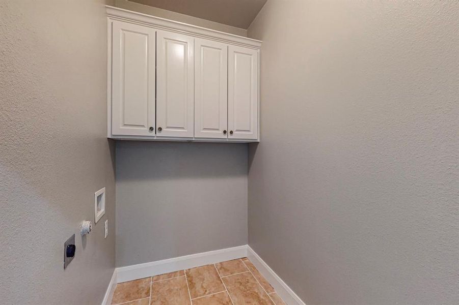 Laundry room with light tile patterned floors, cabinets, hookup for an electric dryer, and hookup for a washing machine