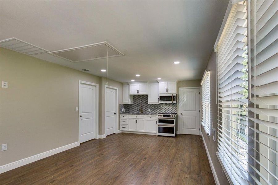 Kitchen with white cabinets, appliances with stainless steel finishes, tasteful backsplash, recessed lighting, and dark wood-style floors