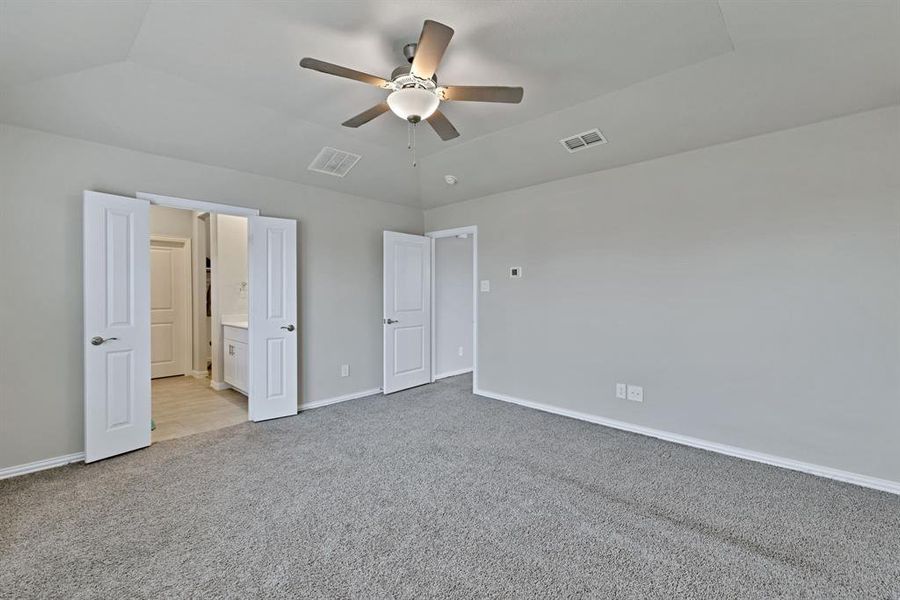 This room features a ceiling fan with integrated lighting, grey carpeting, and light-colored walls
