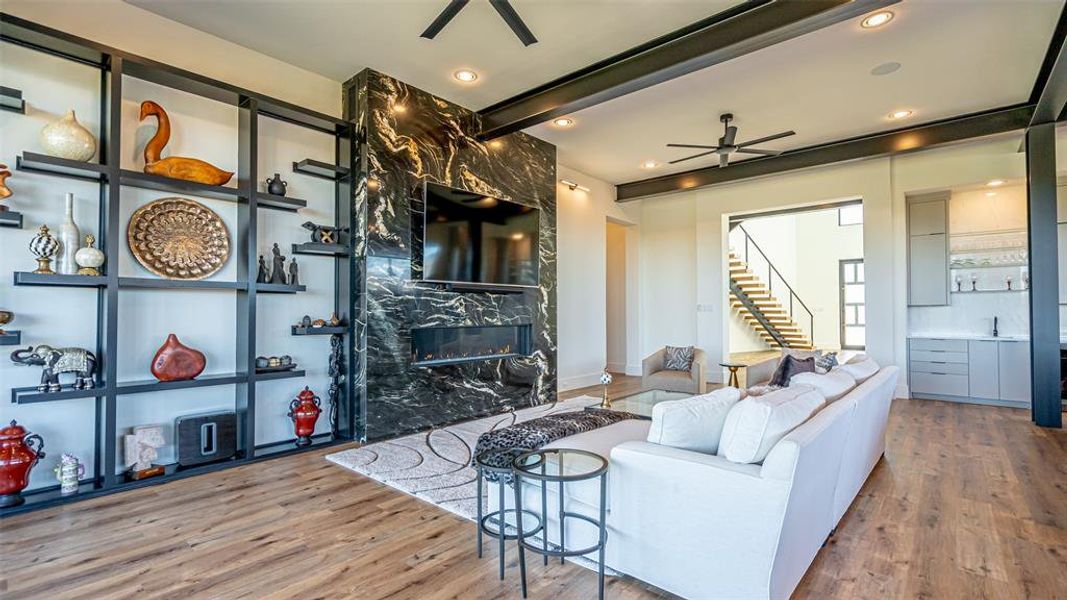 Living room featuring sink, hardwood / wood-style flooring, ceiling fan, a premium fireplace, and beam ceiling