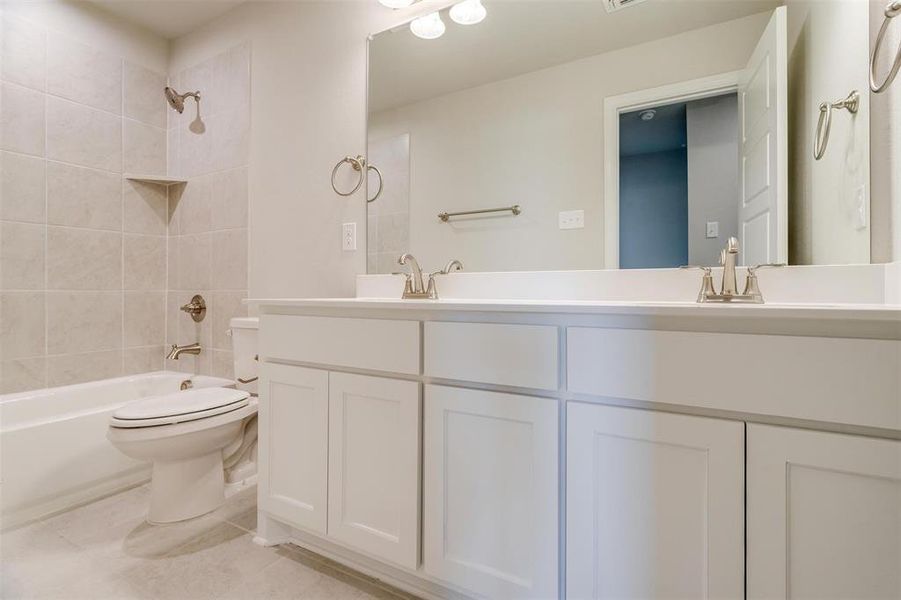 Full bathroom with tile patterned flooring, vanity, toilet, and tiled shower / bath
