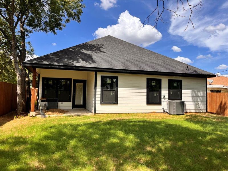 Rear view of property with cooling unit and a lawn