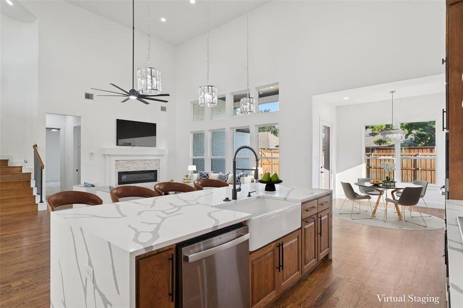 Kitchen with light stone countertops, dishwasher, a kitchen island with sink, a chandelier, and decorative light fixtures