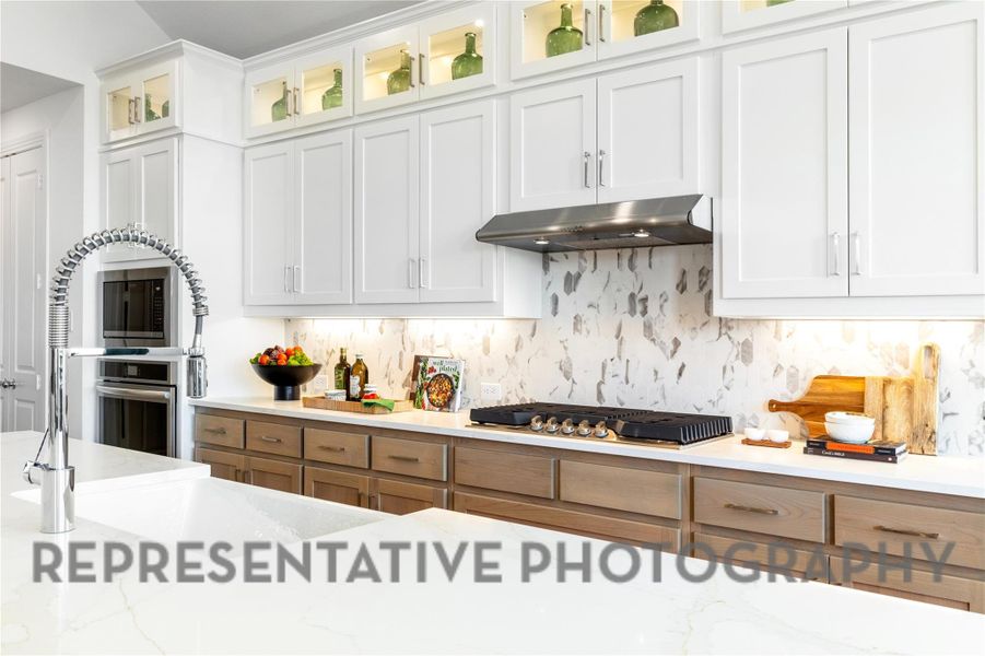 Kitchen with stainless steel appliances, decorative backsplash, under cabinet range hood, and white cabinetry Kitchen with stainless steel appliances, decorative backsplash, under cabinet range hood, and white cabinetry
