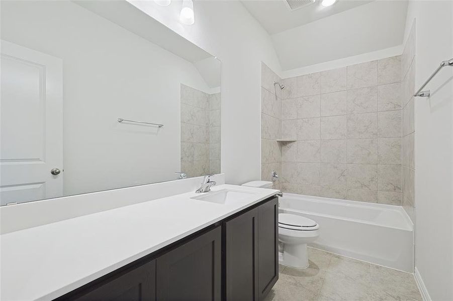 Bathroom with vanity, bathtub / shower combination, and vaulted ceiling