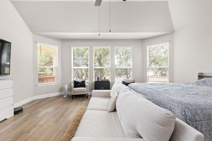 Bedroom with light wood-type flooring, a ceiling fan, and vaulted ceiling