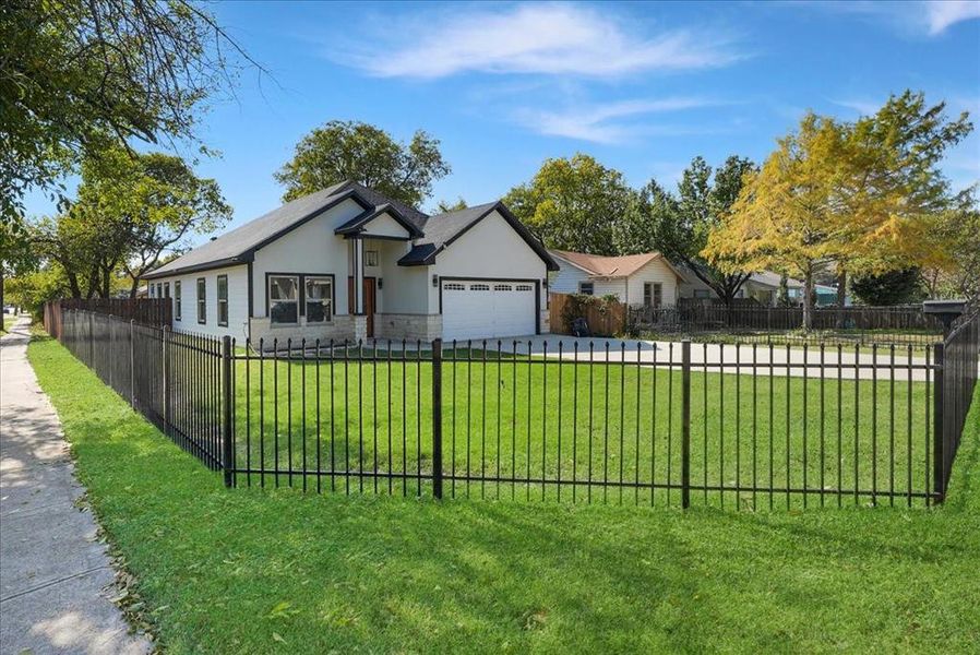 Ranch-style home featuring stucco siding, stone siding, a fenced front yard, an attached garage, and driveway