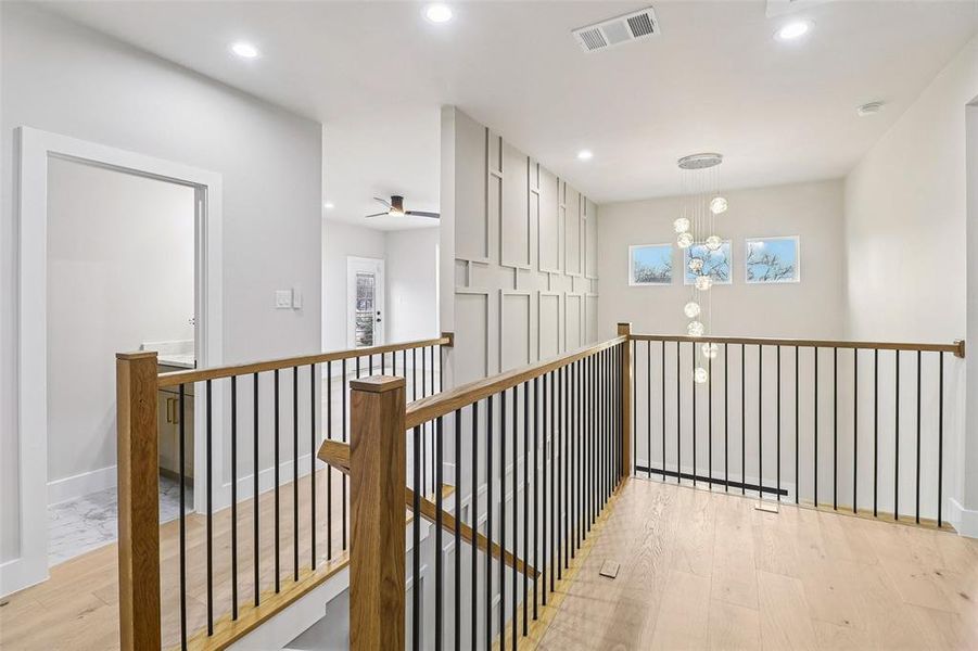 Hall featuring light wood finished floors, recessed lighting, and an upstairs landing