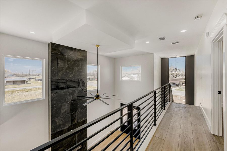 The view from the second floor - tall windows infuse both floors in peaceful natural light while the statement hearth stretches to the ceiling.