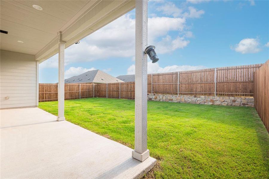 Covered patio with recessed lighting, featuring a concrete surface and a full wooden privacy fence Covered patio with recessed lighting, featuring a concrete surface and a full wooden privacy fence